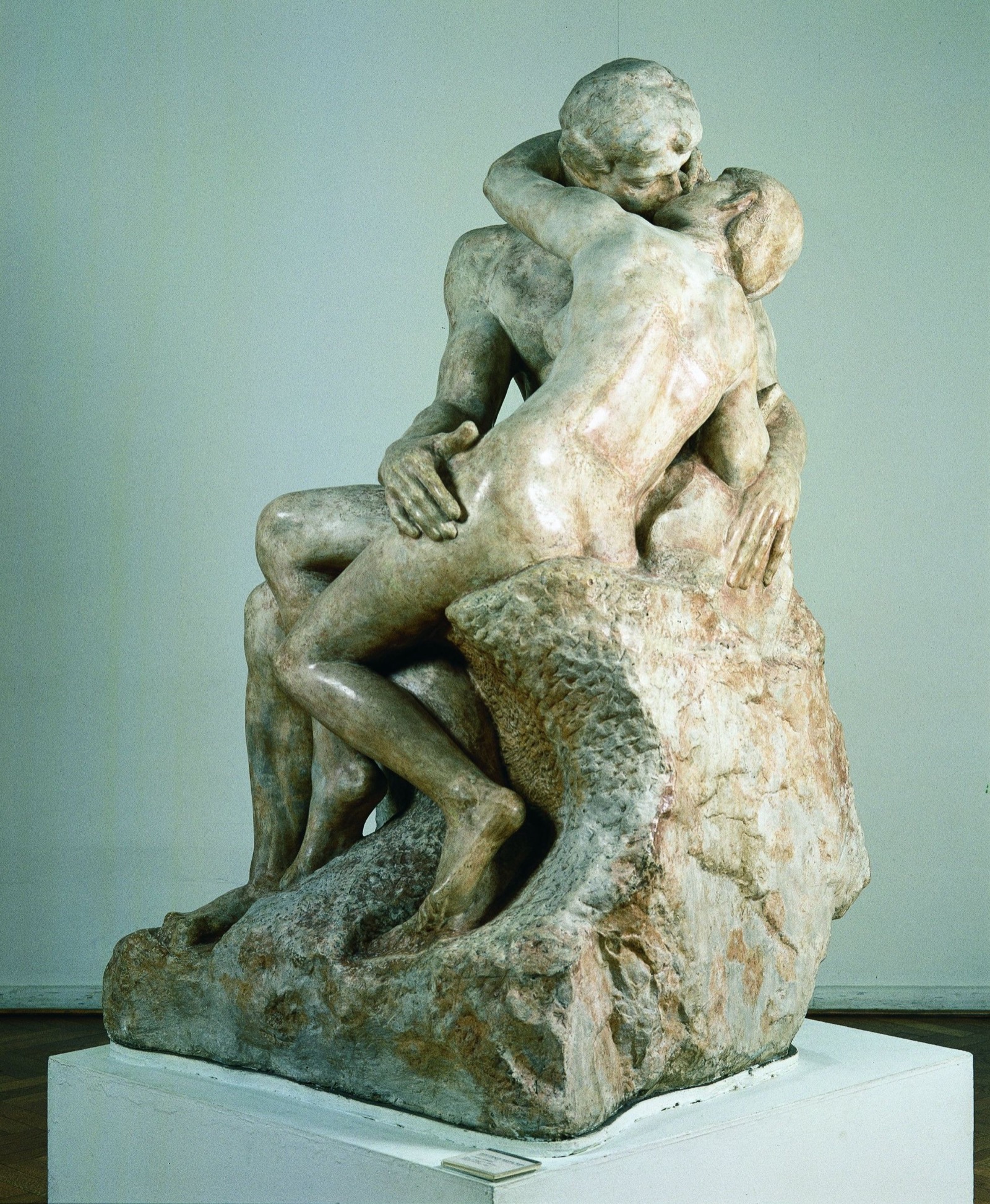 Two nude figures entangled in a kiss, neither dominant, the marble dissolving where their bodies meet — mutual manifold exposure made stone